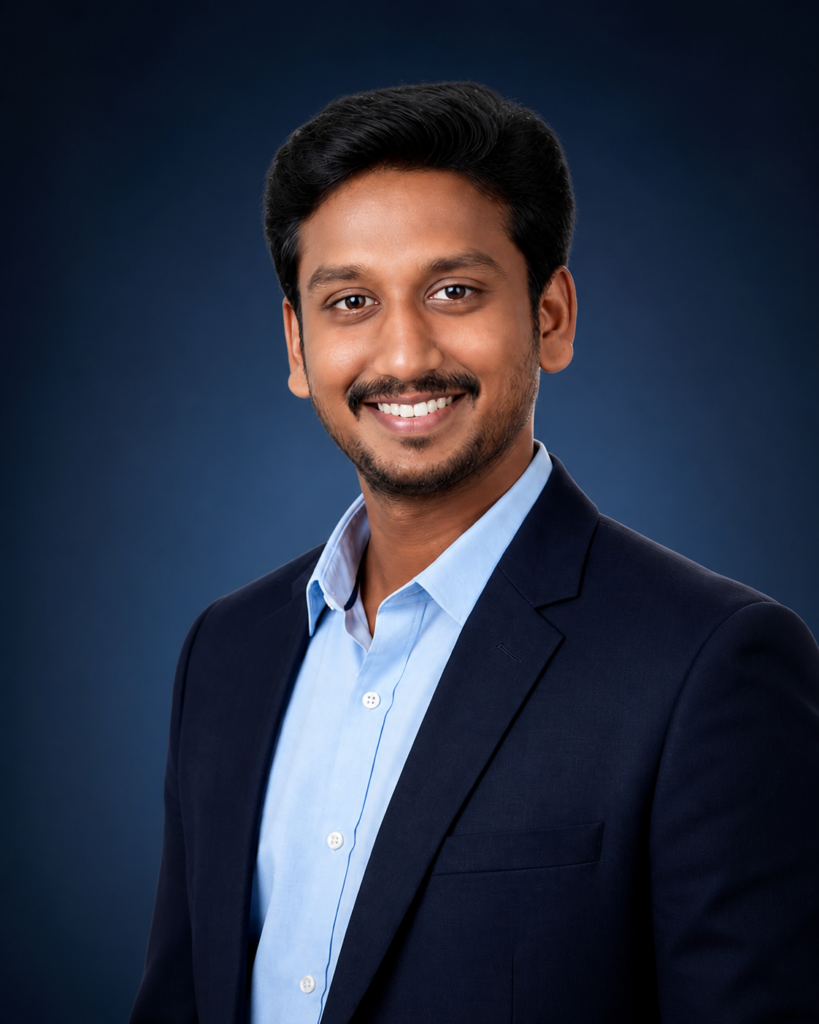 Professional corporate headshot of John Amulraj, founder of OZO DreamFX, wearing a navy blue blazer and light blue shirt against a dark blue studio background